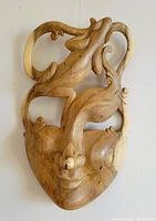 Front view of hand carved wood mask showing detailed facial features and curved design elements.