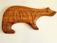 Full view of the wooden bear carving showing its side profile with carved designs on the body.