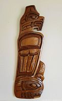 Full view of the carved wooden Thunderbird plaque showing front details and shape.