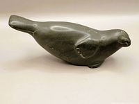 Side view of dark polished stone seal sculpture showing body shape and face details