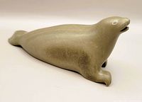 Side profile of the light gray stone seal carving showing open mouth and detailed flippers on front side.