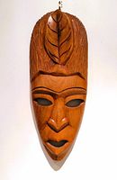 Front view shows the carved facial features and leaf motif on the forehead.