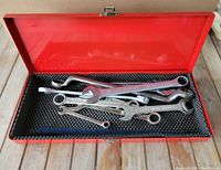Open red metal box with 11 Stanley combination wrenches of various sizes inside on padded lining.