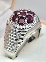 Close-up of ring with ruby cluster set in sterling silver band showing ridged sides and detailed silverwork