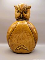 Front view of owl-shaped decanter showing leather wrapping and embossed feather details