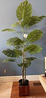 Full view of the artificial Monstera plant approximately 75 inches tall in the wood planter box showing large green leaves.