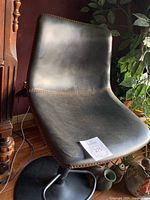 Photo showing the full side view of the black leather swivel bar stool with orange stitching and black metal base.