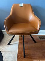 Front view of the butterscotch-colored swivel accent chair with metal legs against a blue wall.