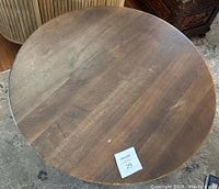 Overhead view of the round dark brown wooden table top with visible scratches.