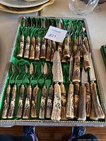 Full tray view of green satin-lined tray holding spoons, dinner knives, carving knife and fork