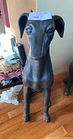 Full frontal photo of the dog statue showing its sitting posture and smooth metal surface.