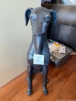 Full front view of the metal dog statue showing the sitting pose and overall condition.