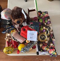 Photo showing mixed lot with Monopoly board game, sunglasses, red toy car, View-Master, wolf plush, wolf statue, and birthday sparklers.