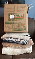 Folded stack of blankets and a U-Haul box on couch