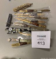 Photo showing 12 letter openers with varied styles and plastic sleeves.