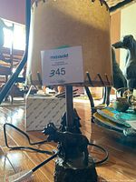 Full view of the metal moose lamp with attached cord and the lampshade with black stitched edges.