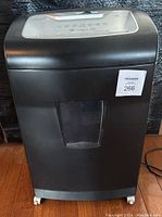 Front view of black Staples paper shredder showing transparent bin window and caster wheels.