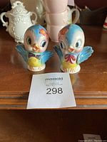 Front view of two blue bird salt and pepper shakers with facial details and flower accents.