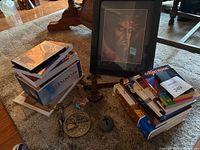 Full lot overview showing framed religious picture, books, rock with cross, medallion, and crucifix statue on floor