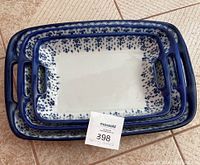Three nested rectangular blue and white WCL pottery baking dishes with handles, showing top-down view and pattern detail.