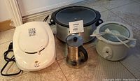 Photo of George Foreman Lean Mean Fat Grilling Machine grill, two slow cookers, and stainless steel espresso maker.