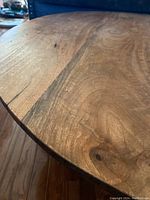 Close-up of the solid wood round tabletop showing natural grain and knots.