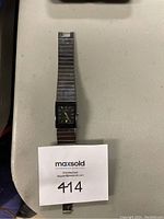 Full view of watch laid flat, displaying band and dial with auction tag