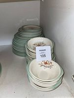 Stack of Wedgwood plates and bowls showing the green rim and floral design on the dinnerware.