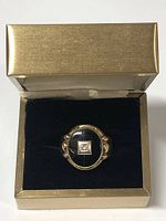 Ring in presentation box showing oval onyx top and decorative shoulders