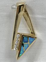 Front view of triangle pendant showing opal inlays and diamonds
