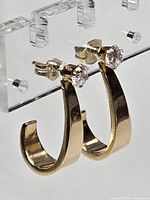 Pair of 14Kt yellow gold J-Hoop earrings with cubic zirconia studs shown from side angle, highlighting the thickness and gold color.