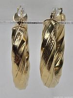 Pair of earrings hung on clear stand, front view