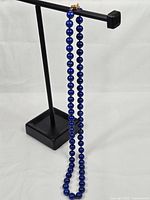 Full view of necklace displayed on stand showing drape and clasp location