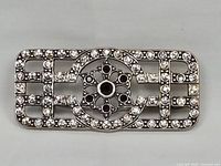 Front view of rectangular Art Deco sterling silver brooch with clear and red stones.