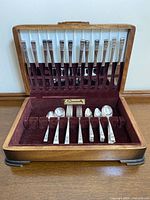 Full view of the open wooden case displaying the silverplate flatware set including knives, spoons, forks, and a small spoon arranged in velvet slots.