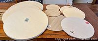 Top view of ten round discs and trays on wooden table showing varying sizes and materials including plywood and MDF with smooth and rimmed edges