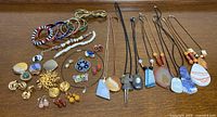 Full lot of mixed jewelry spread out showing necklaces, bangles, brooches and earrings.
