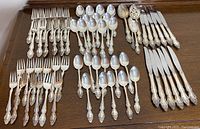 Overview of all pieces arranged on table: forks, knives, tablespoons, teaspoons, serving spoons