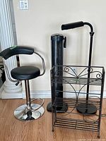 Bar stool, metal shelf, floor lamp, and fan grouped together in room