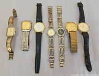 Seven wristwatches laid out side by side showing entire lot