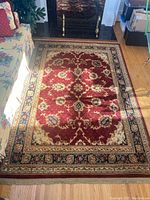 Full view of red oriental area rug on hardwood floor near sofa and glass coffee table