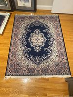 Full view of the synthetic area rug laid flat on a wooden floor showing the central medallion and floral patterns.