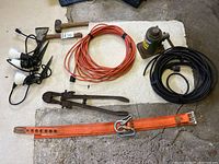 Overview of all items including car jack, orange safety harness, bolt cutters, extension cords, garden lights, axe and hammer, wooden mallet.