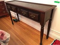 Left angled front view showing dark wood finish, brass handles on three faux drawers, and tapered turned legs.