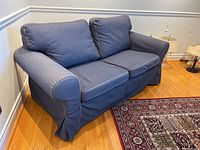 Side view of blue Ikea Ektorp loveseat showing fabric slipcover and rolled arm design.