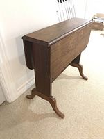 Side view of the small drop leaf table showing the folded leaf on one side and the pedestal leg design.