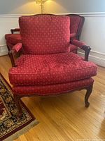 Front view of the custom lounge chair showing red patterned upholstery and carved wooden frame.
