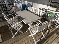 Full view of white wood patio dining table with six matching chairs on deck