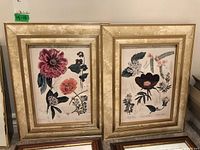 Two framed floral prints side by side on a shelf showing full artwork and frames.