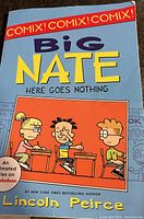 Photo of the front cover of the Big Nate comic book called 'Here Goes Nothing' showing the title, author name Lincoln Peirce, Red 'COMIX!' banner, and cartoon classroom characters.